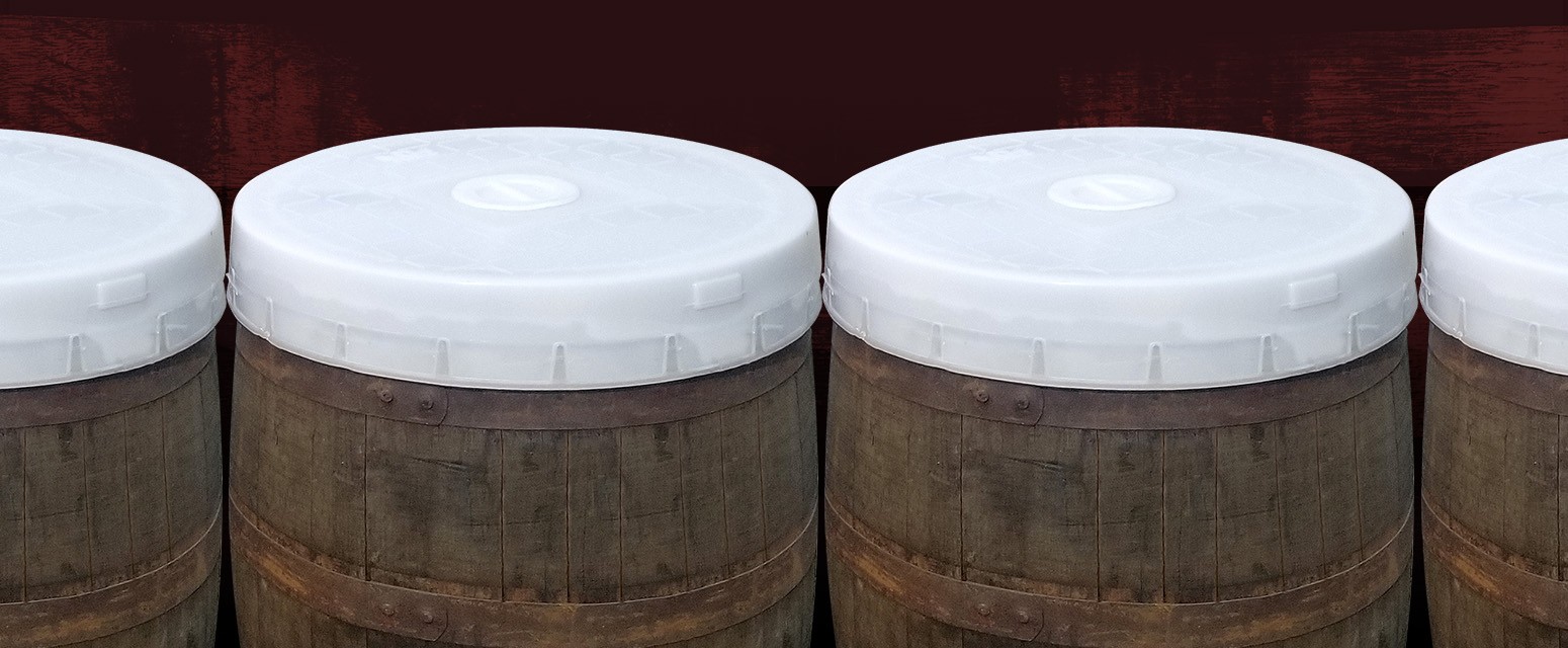 line up of whiskey barrels with spart cap lids